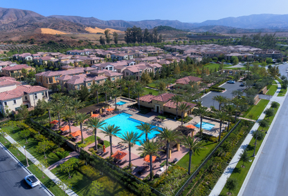 Aerial view of a residential neighborhood in Irvine California featuring a pool, surrounded by homes and greenery.